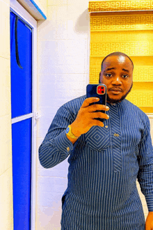 a man in a blue striped shirt is taking a selfie with his cell phone