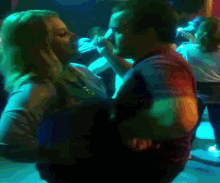 a woman is laying on a man 's back in a dark room