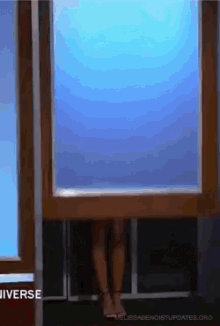 a woman is standing in front of a window with the word universe written on the bottom