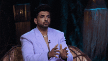 a man in a purple suit is sitting on a chair