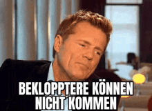 a man in a suit and tie is making a funny face with a caption that says beklopptere können nicht kommen .