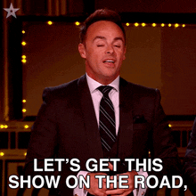 a man in a suit and tie is saying " let 's get this show on the road "