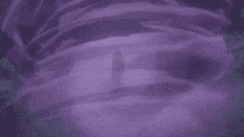a person is standing in the middle of a purple swirl in the dark .