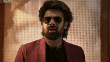 a man with a beard wearing sunglasses and a red jacket with the year 2005