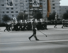 a black and white photo of a parade with a man holding a flag