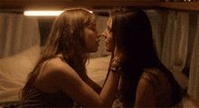 two women are kissing each other on the nose in a dark room