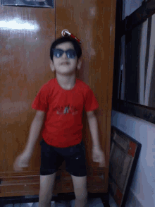 a boy wearing sunglasses and a red shirt that says ' united states of america ' on it