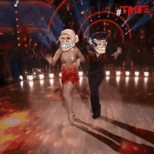 a man and a woman are dancing on a dance floor . the woman is wearing a monkey mask .