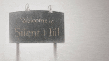 a black and white sign that says `` welcome to silent hill '' is hanging on a white wall .