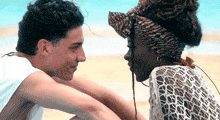 a man and woman are looking at each other on the beach