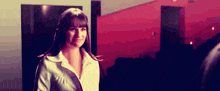 a woman in a white shirt is standing in front of a red wall