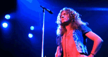 a shirtless man singing into a microphone with a blue background