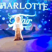 a woman in a white coat is walking on a stage in front of a sign that says harlotte flair