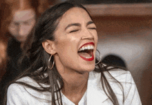 a woman with red lipstick and hoop earrings is laughing with her eyes closed
