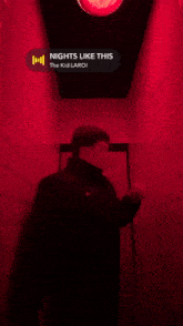 a man leaning against a wall in a hallway with a red light above him that says ' nights like this '
