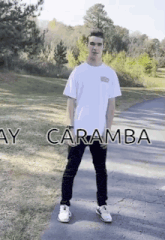 a man wearing a white shirt and black pants is standing on a road with the words ay caramba written on the bottom