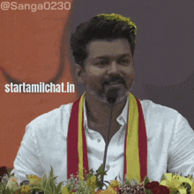 a man speaking into a microphone with the words starttamilchat.in written below him