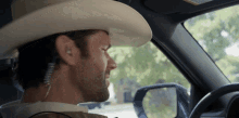 a man wearing a cowboy hat is sitting in a car with his eyes closed