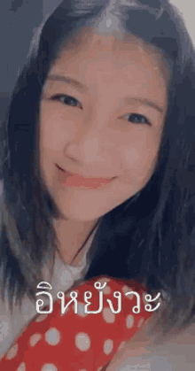 a young girl is smiling and wearing a red and white polka dot scarf around her neck .