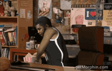 a man sits at a desk with a box of popcorn and a getmorphin.com logo