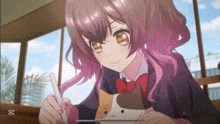 a girl with pink hair is sitting at a table holding a cat and drawing on a tablet .