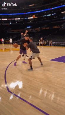 two men are playing basketball on a court with tiktok written on the bottom right
