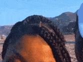 a close up of a woman 's braided hair on a beach