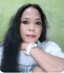 a woman with long black hair is wearing a white shirt and a watch .