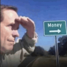 a man stands in front of a green sign that says money