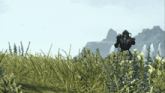 a video game character stands in a field of tall grass with mountains in the background