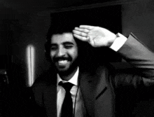 a man in a suit and tie is saluting with his hand on his head