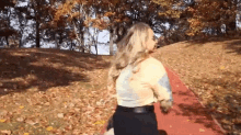 a woman is running on a track in a park with trees in the background