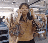 a woman wearing glasses and a plaid shirt is in a clothing store