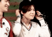 a man and a woman are standing next to each other . the woman is wearing headphones and a hat .