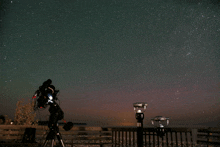 a telescope is sitting on a tripod in front of a starry sky