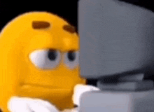 a cartoon smiley face is sitting in front of a computer screen .