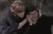 a woman is covering her mouth with her hand while another woman holds her head