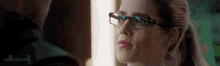 a woman wearing glasses is looking at a man in a mirror .
