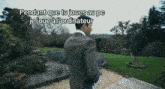 a man in a suit stands in front of a garden with the words pendant que tu joues au pc je joue