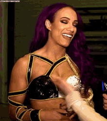 a woman with purple hair is smiling and holding a person 's arm .