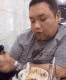 a man is sitting at a table eating a bowl of food with a spoon .