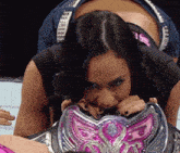 a woman in a black shirt is biting into a pink and silver item