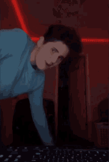 a man in a blue sweater is standing in front of a computer keyboard