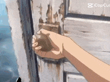 a person 's hand is holding a door knob in front of a sign that says cap cut
