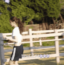 a woman in a white crop top and black shorts is running behind a fence