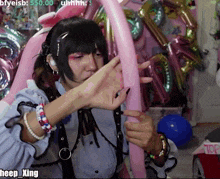 a person is holding a pink balloon in front of balloons and says heep xing
