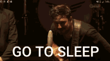 a man singing into a microphone with the words go to sleep behind him