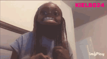 a woman with braids is making a funny face while wearing a hat and a blue shirt .