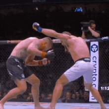 two men are fighting in a cage with a sign that says crypto