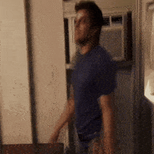 a blurry picture of a man in a blue shirt standing in front of a refrigerator .